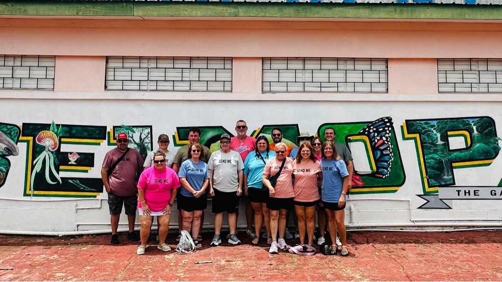 Mission team photo in front of a painted mural in Belize