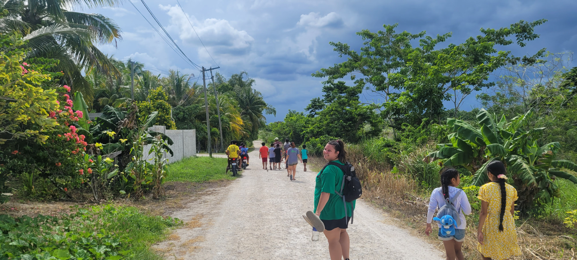 Team walking a village road in Belize with children